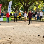 Players enjoying petanque at a warm, sunny FOPI Kota Tomohon event.